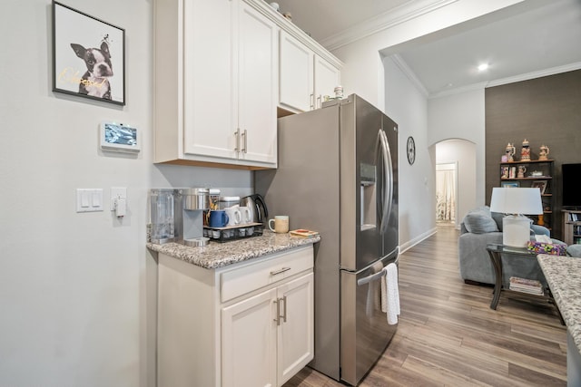 kitchen with light hardwood / wood-style floors, light stone countertops, white cabinetry, and ornamental molding