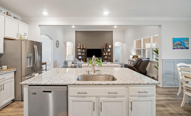 kitchen with sink, white cabinetry, appliances with stainless steel finishes, an island with sink, and light stone counters