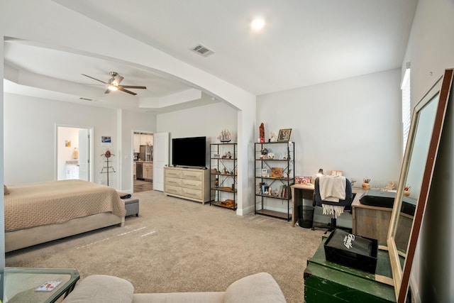 carpeted bedroom with ceiling fan and a tray ceiling