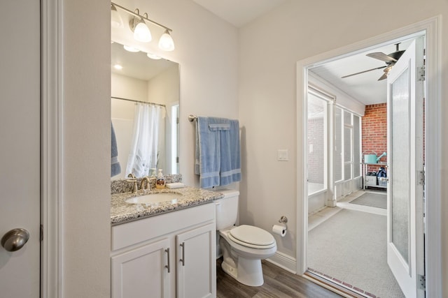 bathroom featuring ceiling fan, vanity, toilet, hardwood / wood-style floors, and curtained shower