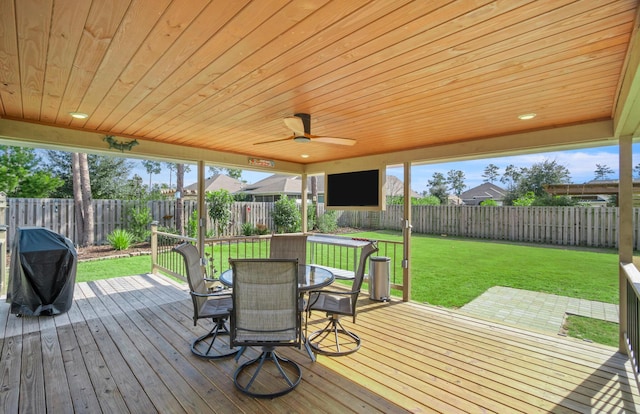 wooden terrace with ceiling fan, a grill, and a yard