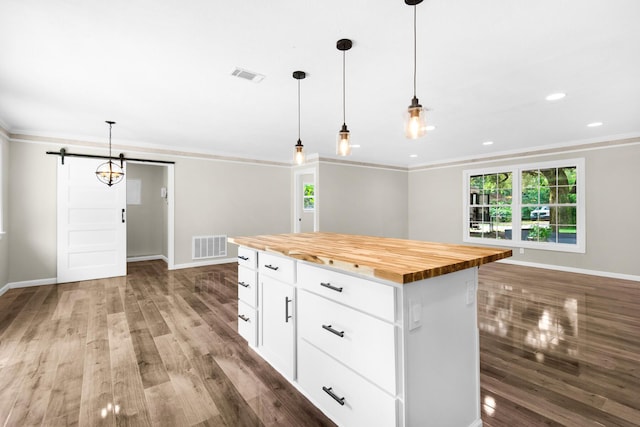 kitchen with a center island, decorative light fixtures, a barn door, wood counters, and white cabinetry