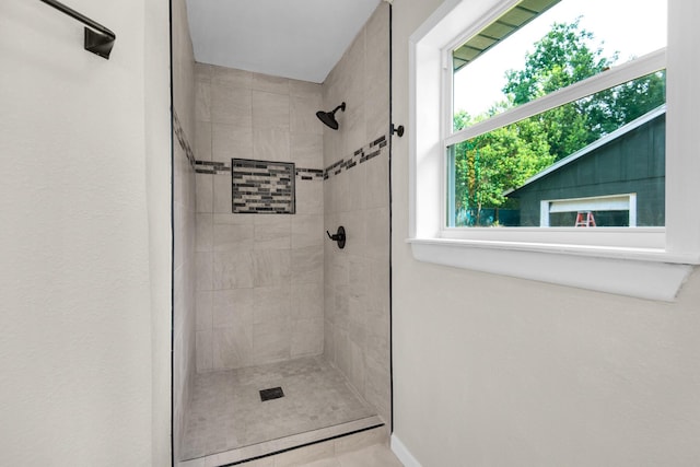 bathroom with tiled shower and tile patterned flooring