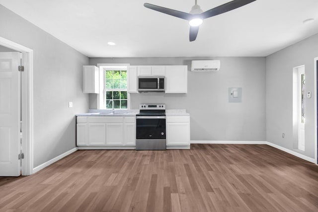 kitchen with white cabinets, ceiling fan, a wall mounted air conditioner, and appliances with stainless steel finishes