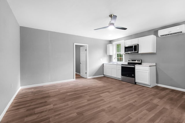 kitchen featuring dark hardwood / wood-style floors, stainless steel appliances, white cabinetry, a wall mounted air conditioner, and sink