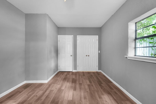 unfurnished bedroom featuring two closets and hardwood / wood-style floors