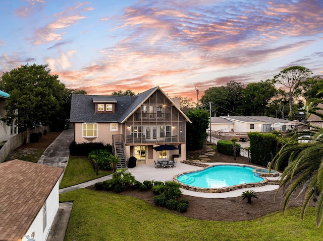 pool at dusk featuring a patio area and a lawn