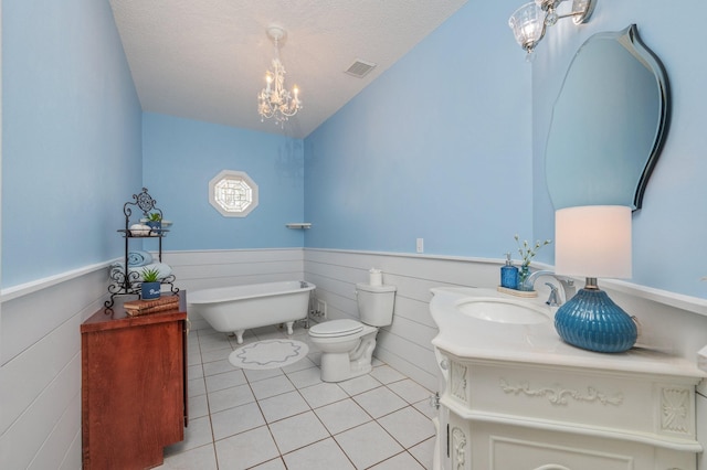 bathroom with an inviting chandelier, vanity, a tub to relax in, a textured ceiling, and tile patterned floors