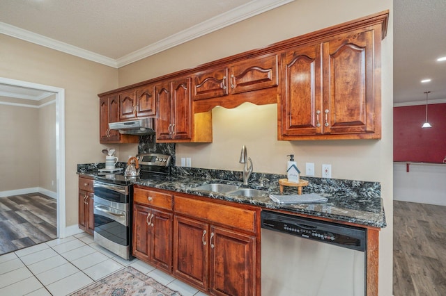 kitchen featuring appliances with stainless steel finishes, dark stone counters, light hardwood / wood-style floors, crown molding, and sink