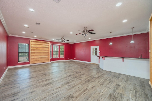 unfurnished living room with a textured ceiling, ornamental molding, hardwood / wood-style floors, and ceiling fan