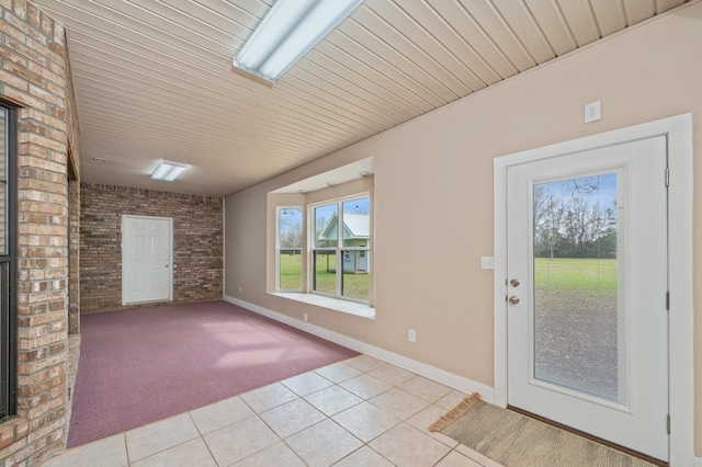 doorway featuring light tile patterned floors, brick wall, and wooden ceiling