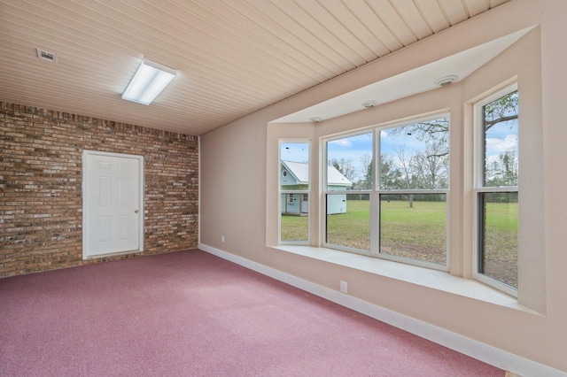 carpeted spare room with brick wall