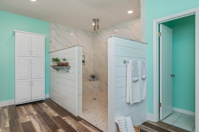 bathroom featuring hardwood / wood-style flooring, a tile shower, and a textured ceiling