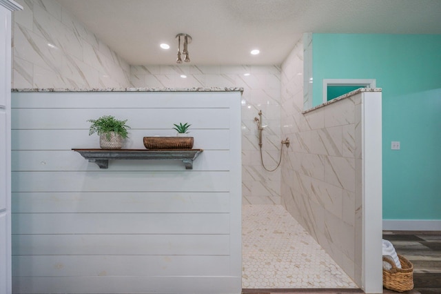 bathroom with a tile shower and hardwood / wood-style flooring