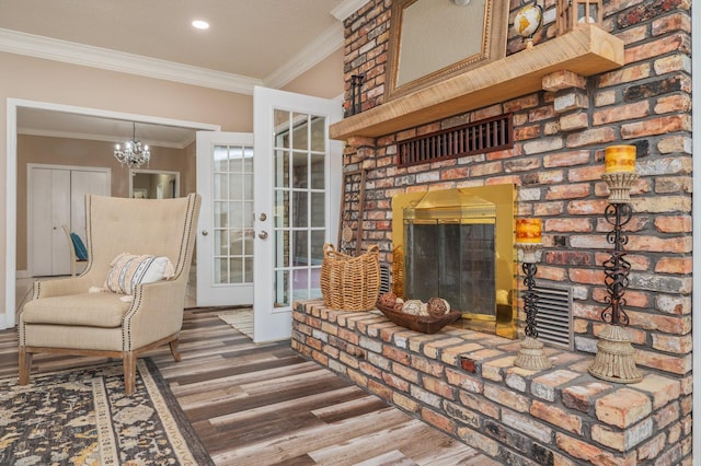 living area with a brick fireplace, an inviting chandelier, wood-type flooring, french doors, and ornamental molding