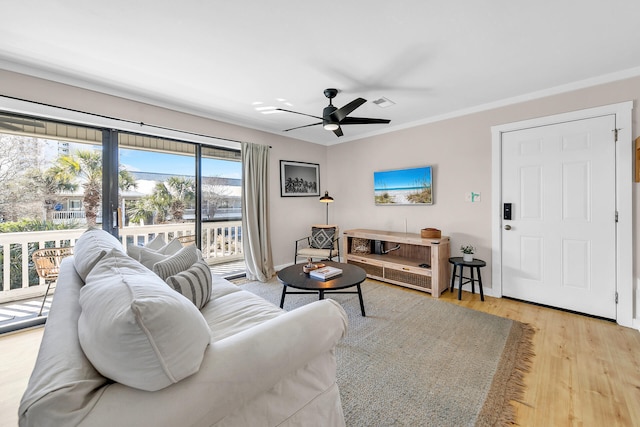 living room featuring ceiling fan, ornamental molding, and light hardwood / wood-style flooring