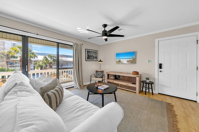 living room featuring ceiling fan, ornamental molding, and light wood-type flooring