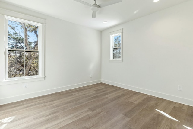 unfurnished room featuring ceiling fan, wood-type flooring, and a wealth of natural light