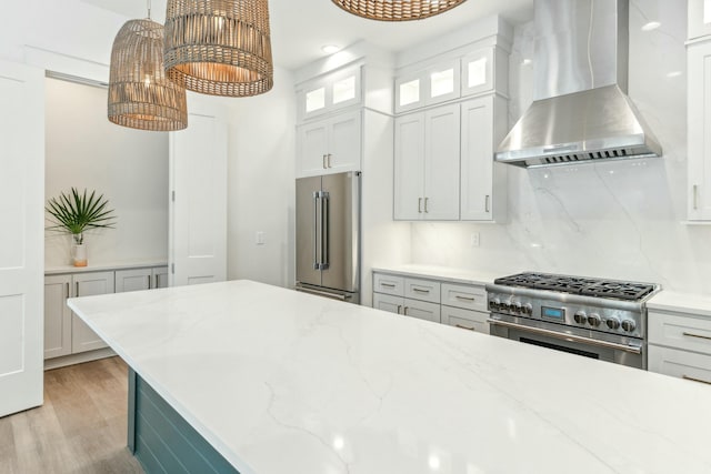 kitchen featuring white cabinetry, hanging light fixtures, backsplash, high end appliances, and exhaust hood