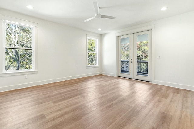 empty room featuring french doors, ceiling fan, a healthy amount of sunlight, and light hardwood / wood-style floors