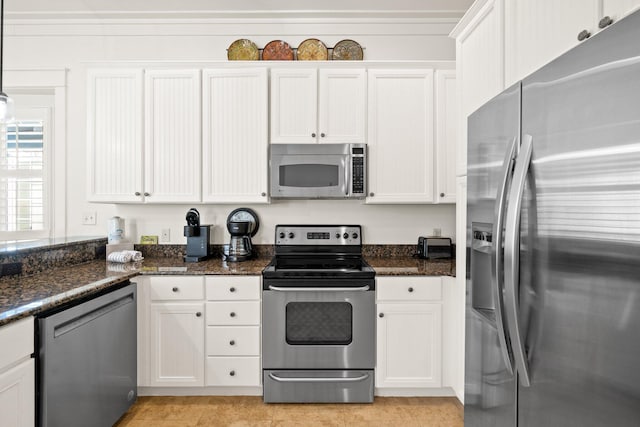 kitchen featuring appliances with stainless steel finishes, dark stone countertops, and white cabinetry