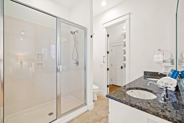 bathroom with toilet, vanity, and a shower with shower door