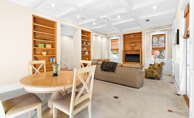 carpeted dining area with ceiling fan, built in shelves, beam ceiling, and coffered ceiling