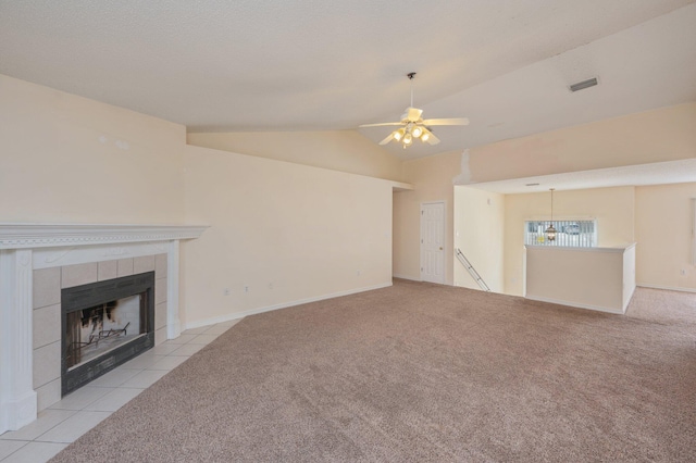 unfurnished living room featuring lofted ceiling, a tiled fireplace, carpet flooring, and visible vents