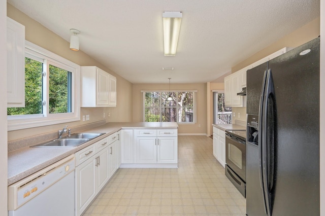 kitchen with light floors, white cabinetry, a peninsula, and black appliances