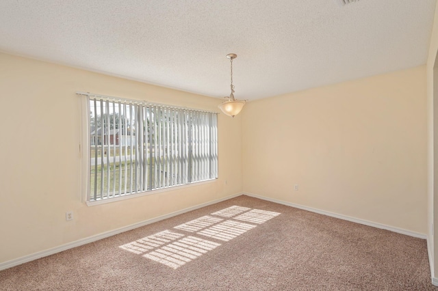 carpeted spare room featuring a textured ceiling and baseboards