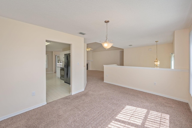 empty room featuring a textured ceiling, baseboards, visible vents, and light colored carpet