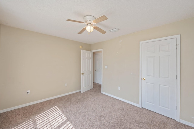 unfurnished bedroom featuring a ceiling fan, carpet flooring, a textured ceiling, and baseboards