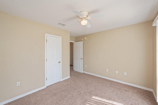 carpeted spare room featuring a textured ceiling, a ceiling fan, visible vents, and baseboards