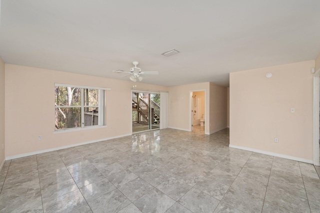 spare room featuring visible vents, a ceiling fan, and baseboards