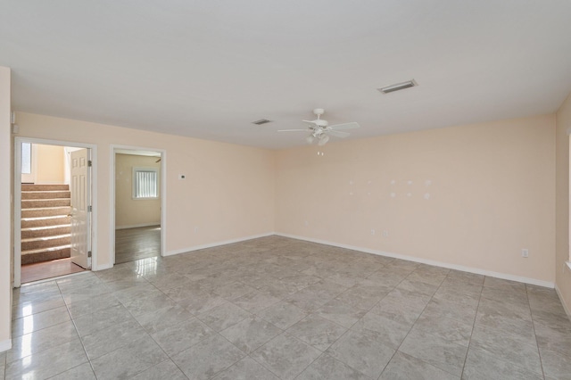 empty room with stairway, baseboards, visible vents, and a ceiling fan