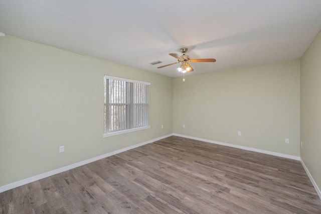 unfurnished room with visible vents, ceiling fan, baseboards, and wood finished floors