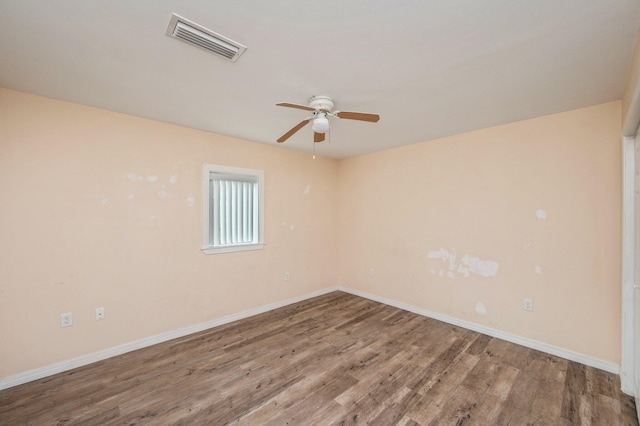 unfurnished room with a ceiling fan, wood finished floors, visible vents, and baseboards