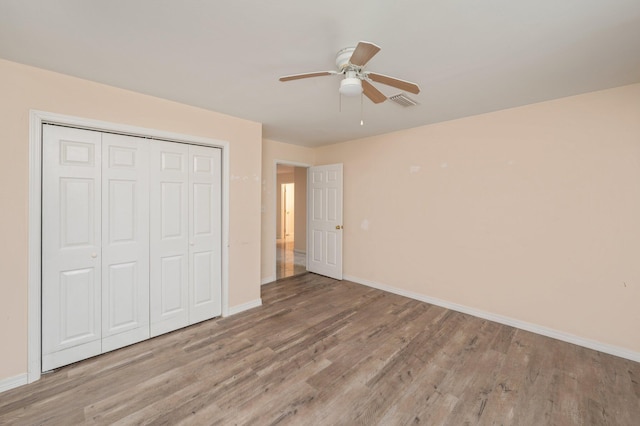 unfurnished bedroom with ceiling fan, a closet, baseboards, and wood finished floors