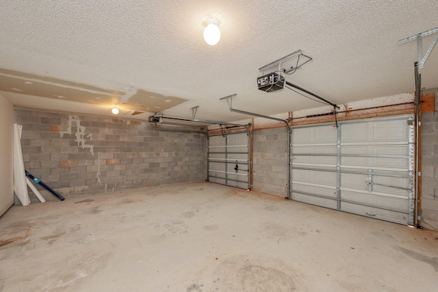 garage featuring concrete block wall and a garage door opener