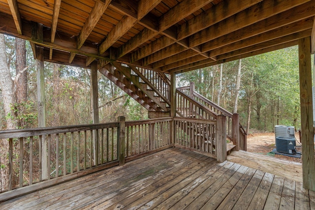 wooden deck with stairs, cooling unit, and a view of trees