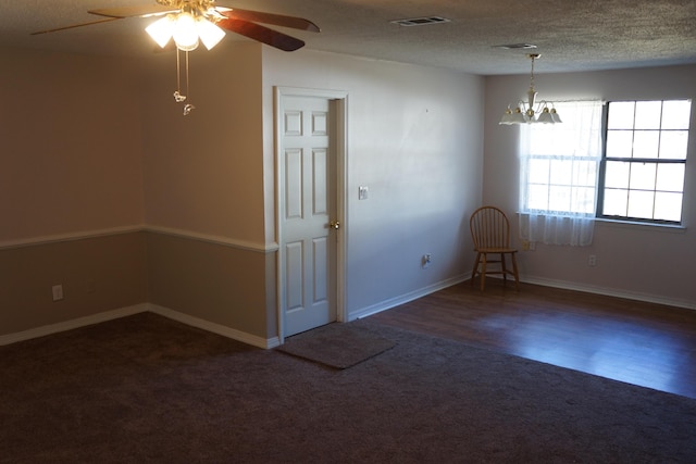 unfurnished room with ceiling fan with notable chandelier, a textured ceiling, and dark carpet