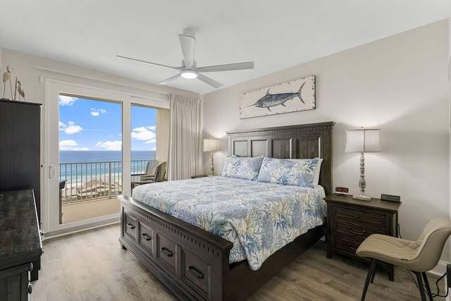 bedroom featuring a beach view, access to outside, a water view, ceiling fan, and light hardwood / wood-style flooring