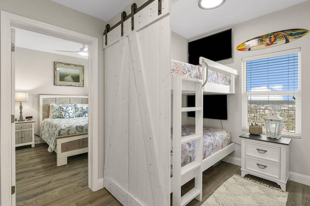 bedroom with a barn door and dark hardwood / wood-style floors