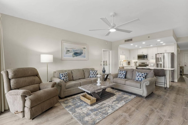 living room featuring ceiling fan, light hardwood / wood-style flooring, and sink