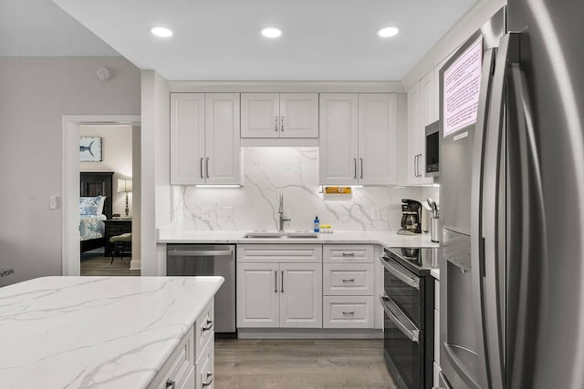 kitchen featuring hardwood / wood-style flooring, stainless steel appliances, tasteful backsplash, white cabinetry, and sink