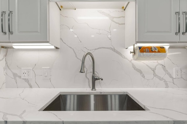 kitchen featuring light stone countertops, white cabinets, and sink