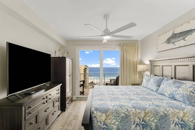 bedroom featuring ceiling fan, light hardwood / wood-style floors, a water view, and access to exterior