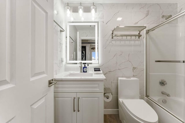 full bathroom featuring toilet, bath / shower combo with glass door, and vanity