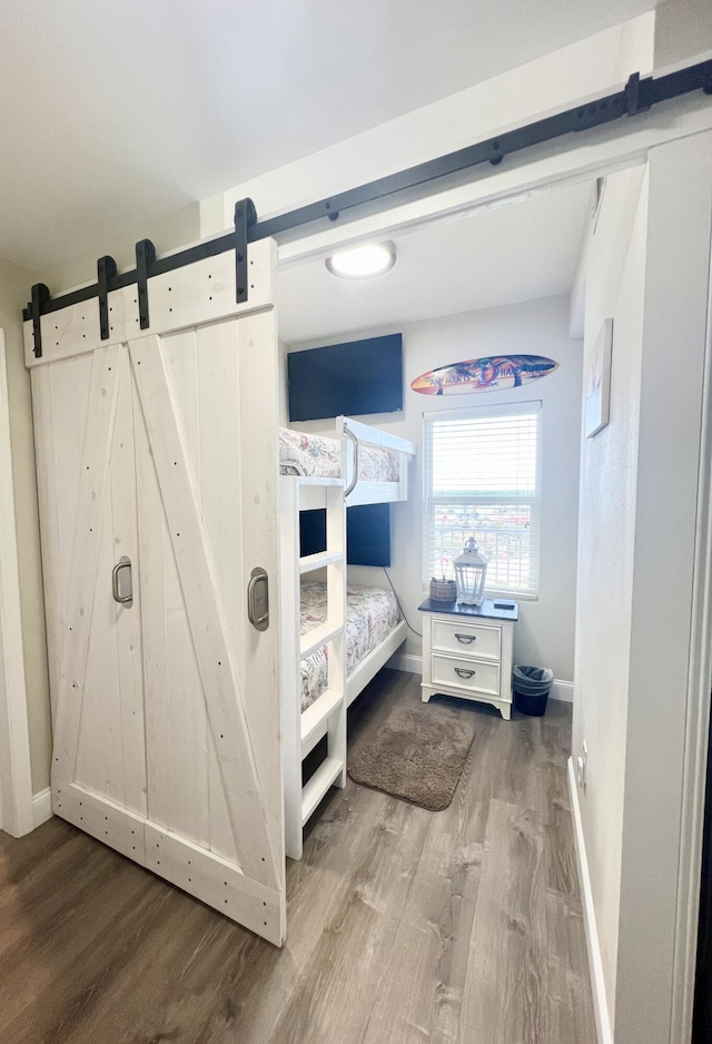 bedroom with a barn door and hardwood / wood-style flooring