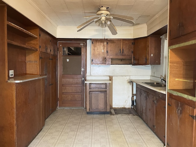 kitchen with dark brown cabinetry, ceiling fan, crown molding, and sink